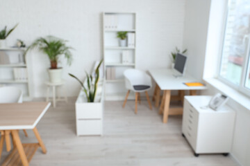 Blurred view of office with table, shelf unit and plants
