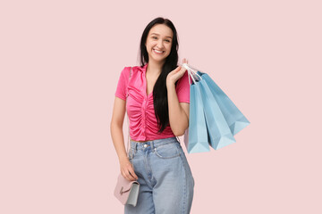 Happy young woman with shopping bags on pink background. International Women's Day