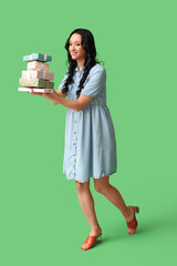 Beautiful young woman with gift boxes on green background. International Women's Day