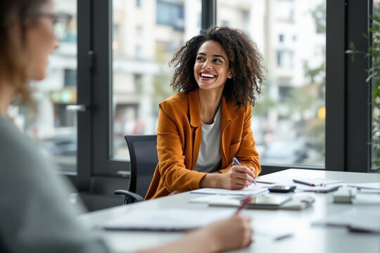 Woman in an orange blazer smiling and taking notes while sitting at a desk in a modern office environment with large windows, concept of collaboration. Ai generative