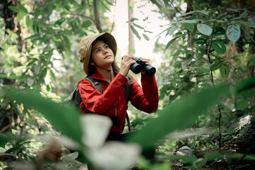 Hikers or explorers on journey carrying backpack, trekking poles and holding binoculars looks into...