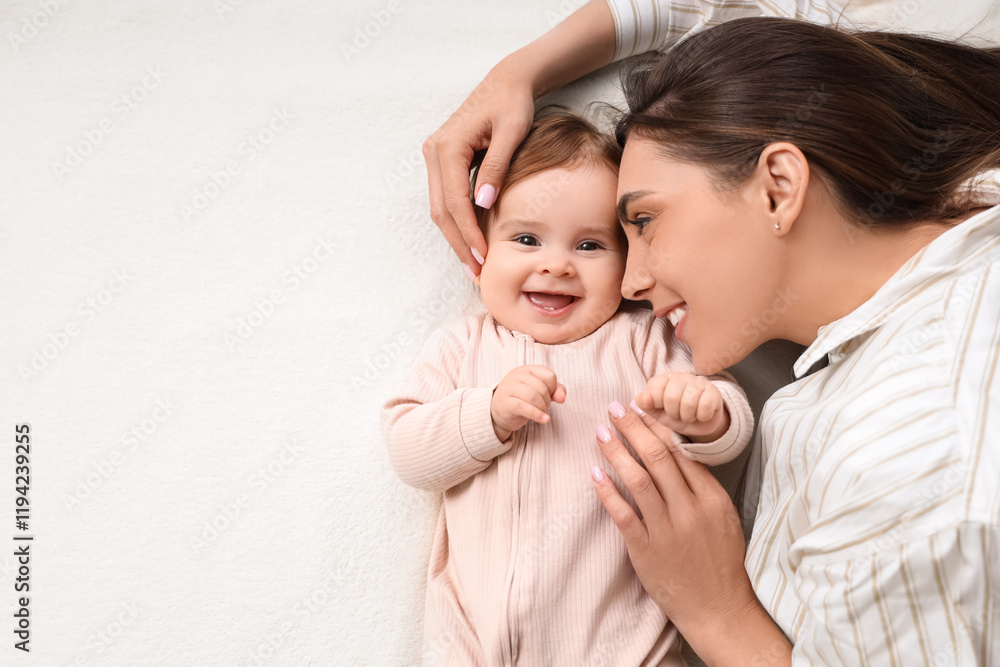 Wall mural Happy young mother with her baby lying on bed at home