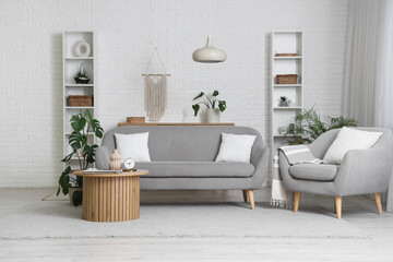 Interior of modern living room with sofa, armchair and stylish coffee table near white brick wall