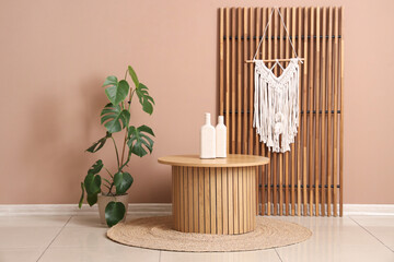 Stylish coffee table with houseplant, rug and decor near beige wall