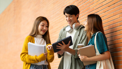 asian group friends student joyfully celebrating with tablet ready for school record at college campus.academic success concept.Students at university with fun for learning,Walking,laughing,bonding.