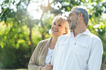 Elderly couple lifestyle concept. Husband embrace wife and sit on seat in the park relax on...
