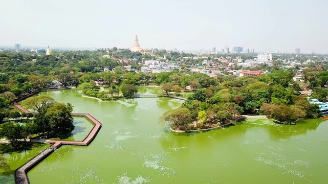 Aerial view of Rangun&rsquo;s Kandawgyi Lake surrounded by lush greenery, with the golden Shwedagon Pagoda in the background. A serene combination of nature, architecture, and urban scenery