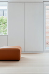 Modern interior featuring a minimalist design with a brown ottoman and natural light