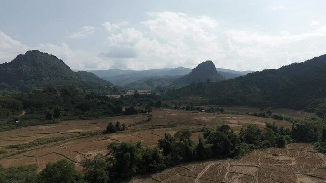 Drone footage above fields in north Laos. Camera is moving foward in a beautiful landscape quiet surrounded by mountains, Luang Prabang province, Lao PDR