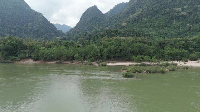Aerial drone footage in green landscape deep vegetation, mountains and over the Nam Ou river, Muang Ngoy, Luang Prabang province, Lao PDR. Camera is moving foward and shows the beauty of the mountains