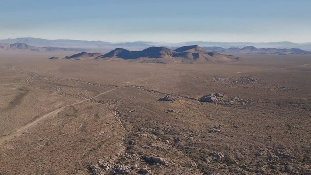 Kelso Pinto Basin Dunes trail road Joshua Tree National Park California aerial drone Yucca Trees San Fernando County Mojave Colorado desert blue sky rugged hill rock formation sunny afternoon forward