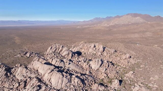 Kelso Pinto Basin Dunes Joshua Tree National Park California aerial drone Yucca Trees San Fernando County Mojave Colorado desert blue sky rugged hill rock formation sunny afternoon circle right down