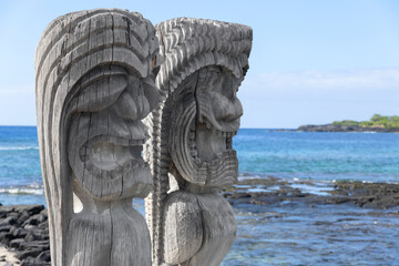 Wooden carved statues of Hawaiian gods, Protectors ki'i, at the shore of Pacific ocean. Puʻuhonua...