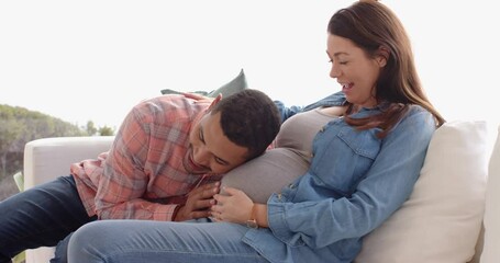 Expectant father listening to pregnant belly, smiling mother sitting on couch