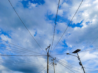 electric pole with wires on a background of clear blue sky and white clouds in the afternoon