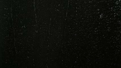 Closeup water rainfall, rain drops falling on window glass over black background - Powered by Adobe
