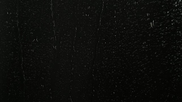 Closeup water rainfall, rain drops falling on window glass over black background