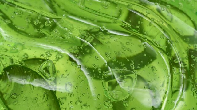 Serum gel texture with aloe vera leaf slices, green transparent cream background