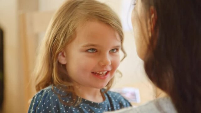 Close up of daughter sitting on mother's lap at home playing thumb war game together and laughing - shot in slow motion