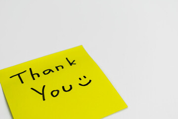 close up of hand writing thank you words sticky notes on white desk background