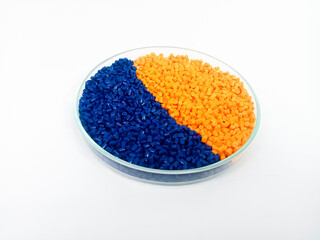 Colorful masterbatch plastic granules in transparent glass cup, polymer carrying pigment poured in white background, suitable for product catalog design of plastic manufacturing industry company profi