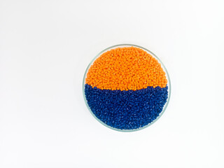 Masterbatch plastic, colorful polymer granules carrying pigments are poured into a glass cup with...