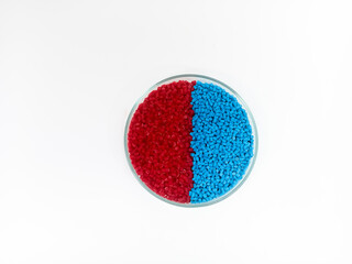 Masterbatch plastic, colorful polymer granules carrying pigments are poured into a glass cup with...