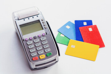 Credit card payment terminal with colorful credit cards on white background.
