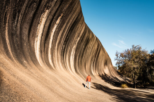 Man looking up at bizarre rock formation, Wave Rock, Australia