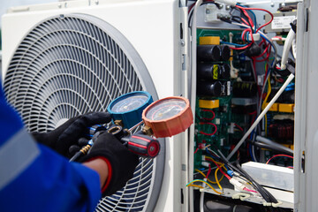 Air conditioner service .The air conditioner technician is using a gauge to measure the refrigerant...