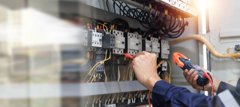 Checking the electrical system, an electrician is using an electric meter to check the electrical system at a control cabinet. for safety
