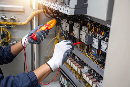 Checking the electrical system, an electrician is using an electric meter to check the electrical system at a control cabinet. for safety