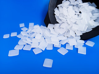 hot glue, dry glue beads, hot melt polymer, black cup isolated on blue background, for product...