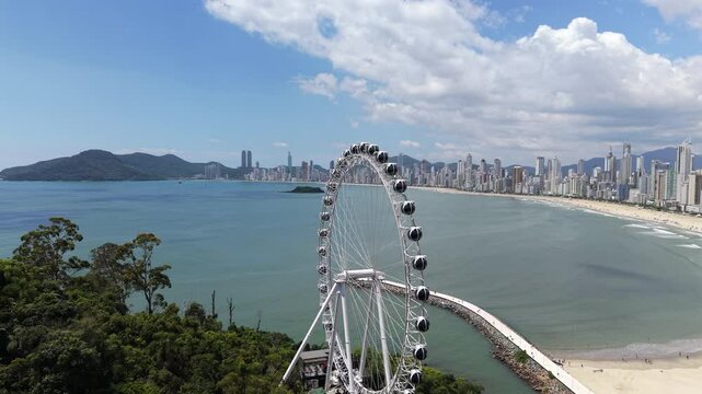 Aerial view of FG ferris wheel on Cambori&uacute; Balne&aacute;rio beach with sea and skyscrapers in background. Brazil