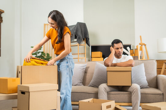 Young couple experiencing relationship issues,gathering belongings, packing items into box,engaging in arguments,expressing emotional frustration,seeking resolution,demonstrating tense body language