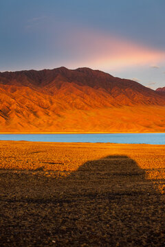 Road trip through national natural parks of Kazakhstan. Shadow of a car on arid steppe land against the backdrop of lake bartogay near tian shan mountains.