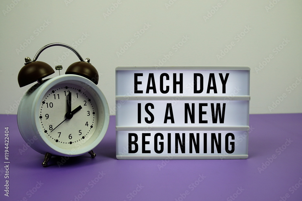 Poster each day is a new beginning text on light box with alarm clock on purple background