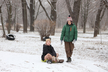 Children are walking, hiking,, sledding and playing in a snowy park. Winter fun and outdoor activities with kids