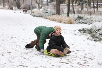 Children are walking, hiking,, sledding and playing in a snowy park. Winter fun and outdoor activities with kids