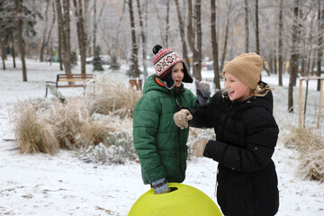 Children are walking, hiking,, sledding and playing in a snowy park. Winter fun and outdoor activities with kids