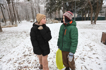 Children are walking, hiking,, sledding and playing in a snowy park. Winter fun and outdoor activities with kids