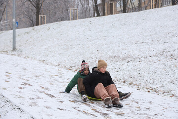 Children are walking, hiking,, sledding and playing in a snowy park. Winter fun and outdoor activities with kids