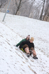 Children are walking, hiking,, sledding and playing in a snowy park. Winter fun and outdoor activities with kids