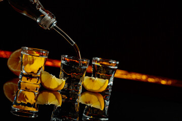 Vodka and lemon slices on a black background.