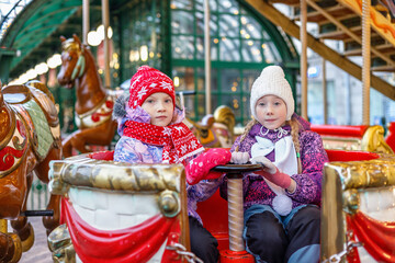 Obraz premium Two little toddler girls on a christmas market, outdoors. Happy children having fun. Holiday, lifestyle concept.