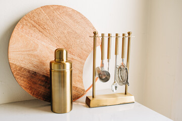 Wooden Cutting Board and Gold Cocktail Mixing Set on White Counter