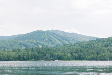 Serene mountain view with a ski slopes and calm lake in front.