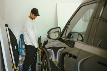 Person charging an electric vehicle inside a home garage