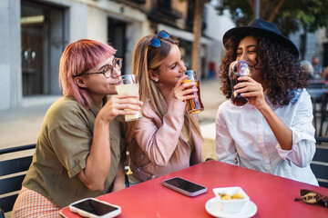 Three young women drinking and having fun at outdoor cafe