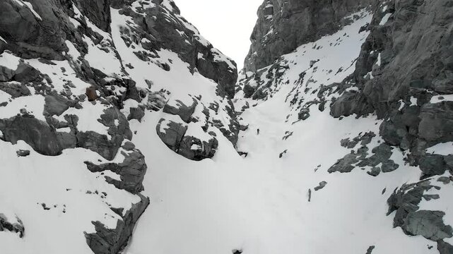 Aerial flyover through Gornerschlucht canyon in Zermatt, Switzerland on a cloudy winter day towards Monte Rosa peaks and Gorner glacier valley.